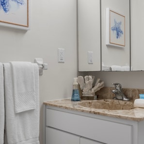 This coastal full bath features a single vanity & shower/tub combo