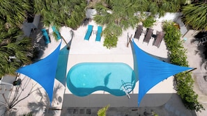 Aerial View of the pool and patio with the shade sails and the chaise loungers.