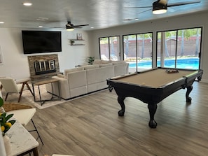 Lovely game room has elegant seating, pool table and view of the outdoor pool.