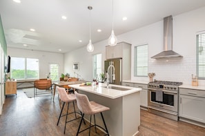 Bright open-concept kitchen featuring a quartz-topped island with bar seating, stainless steel appliances, and abundant natural light streaming through the windows.