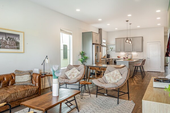 Welcoming living area with a vibrant green accent wall, large Smart TV, and plush seating arranged to take in the serene outside views.