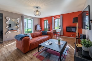 Ferienwohnung Müritzperle Wohnzimmer mit rotem Sofa und modernem Spiegel