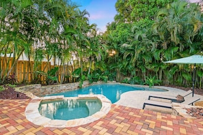 Escape to a private backyard paradise with a sparkling pool and lush greenery, ideal for relaxation in the Florida sunshine.