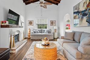 Relaxing living room features high ceilings, comfortable sofas, and a charming fireplace.