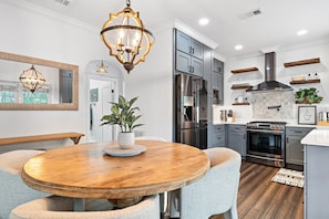 A stylish dining area with a round wooden table sits adjacent to a well-appointed, modern kitchen, perfect for gatherings.