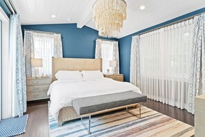 Serene bedroom boasts blue accent walls, a comfortable bed with soft white linens, and elegant sheer curtains.
