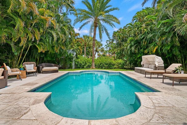 Another view of the inviting pool area highlights the comfortable lounge chairs and the tropical ambiance created by the surrounding palms.
