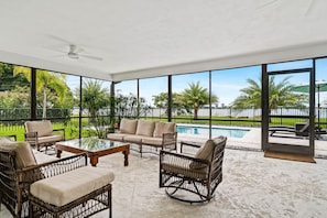 Bright sunroom features floor-to-ceiling windows offering panoramic views of the outdoors and comfortable wicker furniture.
