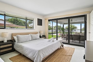 Serene bedroom offers a comfortable king-sized bed and large sliding glass doors leading to a balcony with water views.