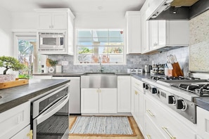 Modern kitchen showcases sleek white cabinetry, stainless steel appliances, and a dark countertop with a view from the window.