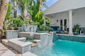 Stunning backyard oasis showcases a multi-tiered pool and spa surrounded by lush tropical landscaping, perfect for relaxation.