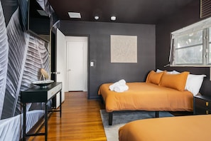 Modern bedroom with dark walls features a comfortable bed with warm orange bedding and unique abstract artwork on the wall.