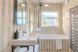 Modern bathroom with a rain shower, bathtub, and stylish tiles — ideal for unwinding after a busy day.