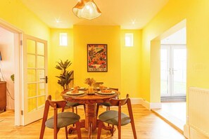 Cosy dining area, perfect for family meals or work, set against cheerful yellow walls and bathed in natural light.