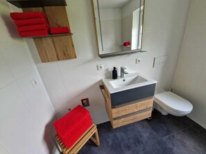 Badezimmer mit Massivholzmöbeln, Handseife, Klopapier und Handtüchern.