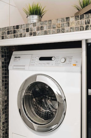 Modern, white dryer nestled within a gray mosaic tiled alcove.