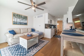 Open layout with cozy living, full kitchen, and view into bedroom.