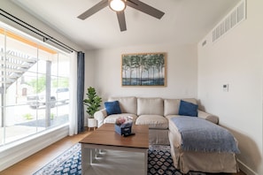 Spacious and cozy living space with a 65" Tv, couch, adjustable coffee table