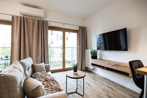 Comfortable living area with a large sofa and TV, perfect for unwinding after exploring Bydgoszcz museums and strolling around Mill Island.