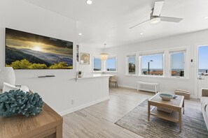 Bright, airy living space with a large TV and sweeping ocean views.