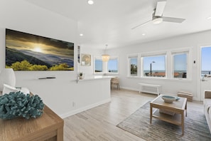 Bright, airy living space with a large TV and sweeping ocean views.