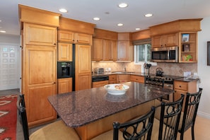 Spacious kitchen with granite countertops and large center island with bar seating for 5. Fully stocked with full size appliances and everything guests need for comfortable meal preparation.