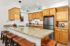Spacious kitchen with granite countertops and large center island with bar seating for 6. Fully stocked with full size appliances and everything guests need for comfortable meal preparation.