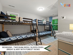 Bright bunk room with cozy beds, playful patterns, and peaceful forest views.