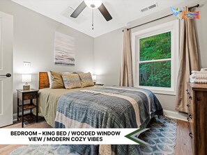 Cozy bedroom with neutral tones, comfy bed, and nature views from window.
