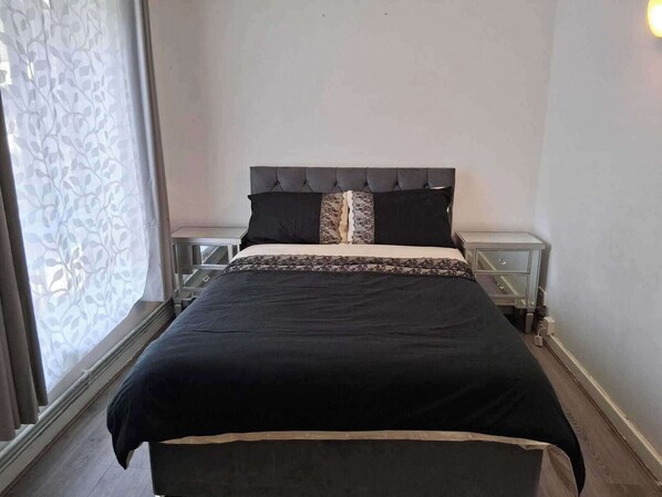 Spacious bedroom with floor to ceiling windows, double bed, 2 bedside tables, double wardrobe with clothes rail and shelves.
