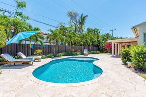 Relax in your own private West Palm Beach oasis—this fully fenced backyard features a sparkling pool, tropical landscaping, covered outdoor dining, BBQ grill, and sun loungers.