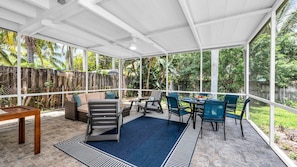 Relax and dine al fresco in the spacious screened-in porch, complete with comfortable lounge seating, a ceiling fan, and outdoor dining for six—all surrounded by lush tropical greenery.