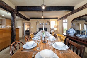 Large hand crafted dining table in front of the open fire.