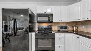 This fully equipped kitchen features black appliances, a filter coffee machine, blender, and plenty of storage. Enjoy both indoor and outdoor dinnerware—perfect for family meals or outdoor dining under the Florida sun.