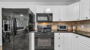 This fully equipped kitchen features black appliances, a filter coffee machine, blender, and plenty of storage. Enjoy both indoor and outdoor dinnerware—perfect for family meals or outdoor dining under the Florida sun.