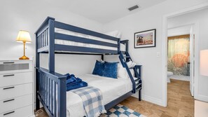 This cozy second bedroom features a stylish navy twin-over-full bunk bed—perfect for kids, teens, or extra guests. With plush bedding, a checkered rug, and playful coastal touches, it’s a fun and functional space the whole family will love.