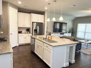 Bright and spacious kitchen designed for convenience and comfort, featuring ample counter space, cabinets stocked with essentials, and a cozy dining area nearby—perfect for enjoying home-cooked meals during your stay.