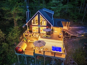From above, the gray-toned cabin nestles seamlessly into the forest, revealing its elegant architecture and tranquil setting in perfect harmony with nature.