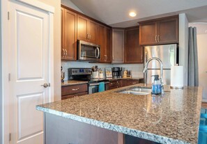 Whip up your favorite dishes in the fully stocked kitchen, featuring stainless steel appliances, a stand mixer, coffee bar, and all the essentials for home-cooked meals.