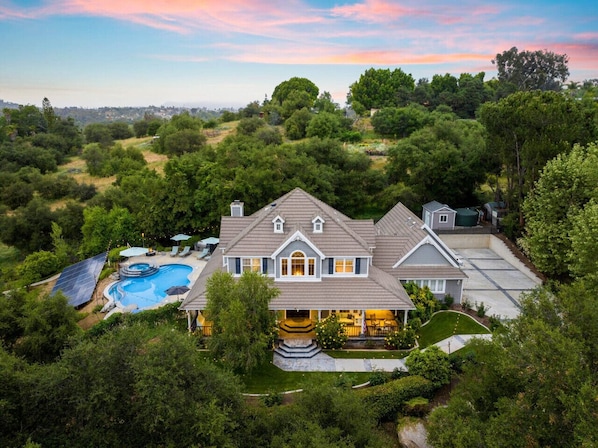 An aerial view showcasing a stunning property with a beautiful pool, spa, and verdant surroundings.