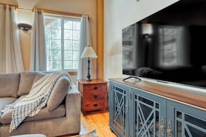 A cozy and welcoming living room featuring soft, comfortable couches arranged around a 55" flat-screen TV. Perfect for movie nights, game days, or simply unwinding after a day of exploring.
