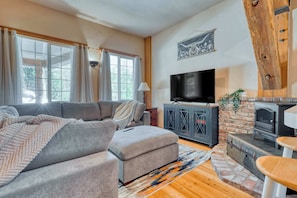The main seating area includes plush, overstuffed couches with accent pillows, providing a comfortable place to relax and enjoy the cabin's rustic charm.