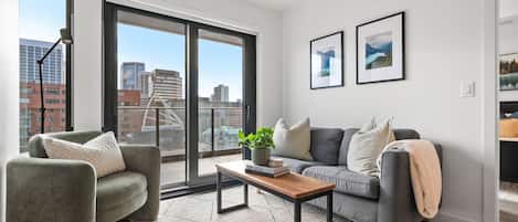 Living room with a Smart TV, board games, cozy seating option & floor-to-ceiling, south-facing windows with access to the wraparound balcony.