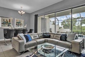 Open living space with large sofa, TV, and back patio access