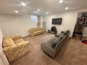 Basement with TV, Couches, bed and a Basketball Set