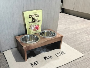 Treat your pet to the best! This setup features a feeder stand, a playful 'Eat Play Love' mat, and tasty Cookie Pal food.