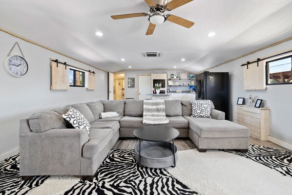 Kick back in this inviting open-concept space featuring a plush sectional, playful zebra-print rugs, and a cozy, well-stocked kitchen—perfect for relaxing after a day of adventure!