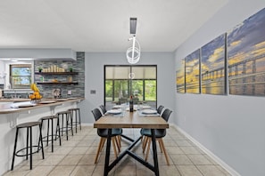 Modern dining area with seating for four to six guests, perfect for shared meals or game nights. Enjoy a seamless flow into the stylish kitchen, complete with bar seating and contemporary finishes. Natural light and scenic views create a welcoming, open-concept space for gathering.