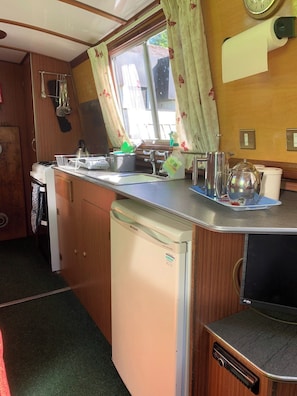 Bright kitchen galley with fridge c/w small freeze box, full size four ring cooker, grill and oven.