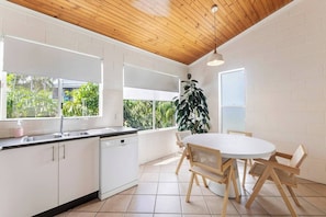 Share meals at the sunny dining table for four, surrounded by lush greenery views.